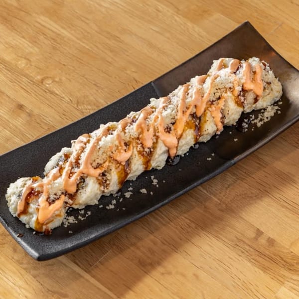 Umami Japanese Cuisine's long sushi roll, drizzled with orange sauce and sprinkled with white flakes.