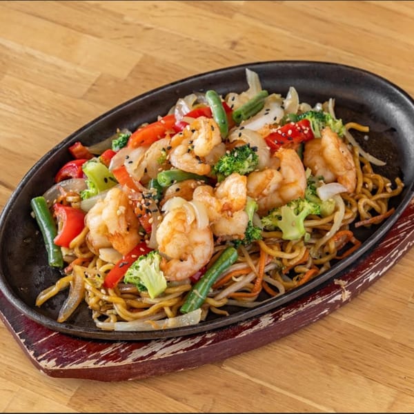 Sizzling Japanese shrimp and vegetable stir-fry with noodles, broccoli, peppers, and sesame seeds.